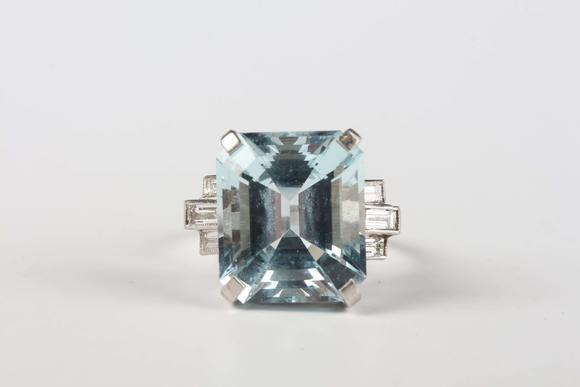TooveysA platinum, aquamarine and diamond ring, claw set with the large cut cornered rectangular step cut aquamarine between baguette cut diamond three stone