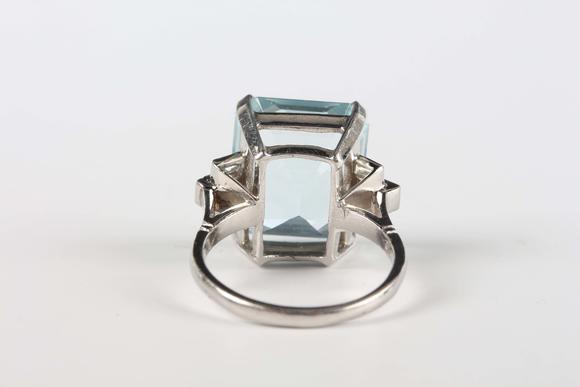 TooveysA platinum, aquamarine and diamond ring, claw set with the large cut cornered rectangular step cut aquamarine between baguette cut diamond three stone