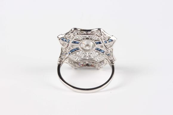 TooveysA platinum, sapphire and diamond ring, collet set with the principal circular cut diamond at the centre, otherwise in a pierced millegrain design, det