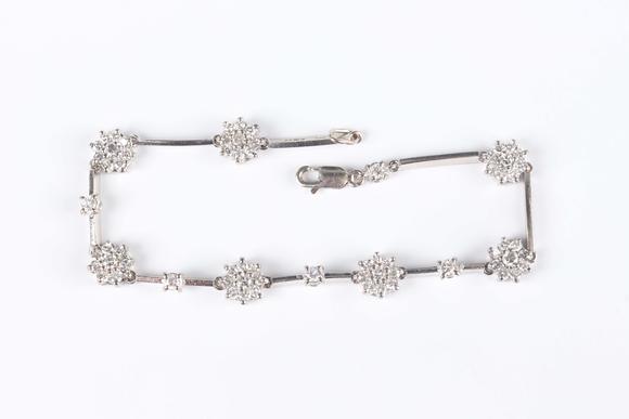 TooveysAn 18ct white gold and diamond bracelet, designed as seven diamond set clusters alternating with four single stone diamond divisions, on a sprung hook