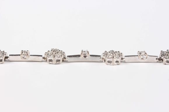 TooveysAn 18ct white gold and diamond bracelet, designed as seven diamond set clusters alternating with four single stone diamond divisions, on a sprung hook