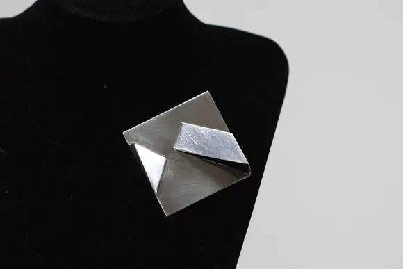 Goldfield Auction sarlsModernist brooch in 925/1000 silver, geometric shape with folded panels in relief, Italian work signed Carlo Lorenzetti, dated 1976.
Limited edition of 28, numbered and signed on the reverse, published by Galleria La Polena, Genoa.
A sculptural aesthetic characteristic of Italian research in the 1970s, in good overall condition.
Condition : Good
Height : 2 cm 
Width : 6 cm
Weight : 32,6 gr
