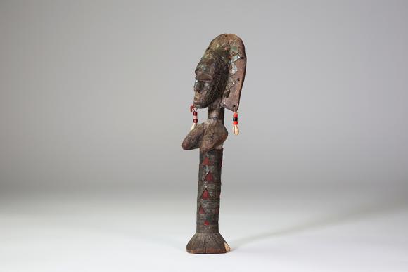 Goldfield Auction sarlsBambara / Marka, Afrique de l’Ouest.
Poupée sculptée, ornée de tissus rouges, de perles, de cauris et de 
plaques de métal gaufrées à décor de scar