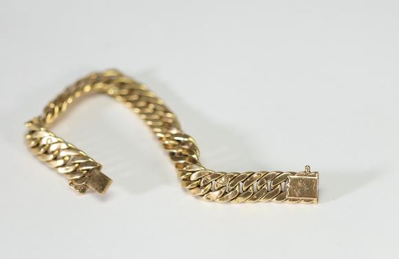 Goldfield Auction sarlsBracelet gourmette ? Caplain Paris ? en or jaune, composé de larges maillons plats et articulés, fermoir mousqueton orné d’un cabochon de saphir bleu