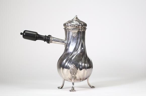 Goldfield Auction sarlsGrande chocolatière en argent massif reposant sur trois pieds cambrés, à décor de c?tes torses et appliques rocaille, bec verseur feuillagé, couvercle