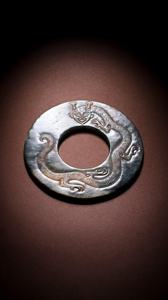 HUNG YUN ZHAI AUCTION HOUSE INCPre-Ming Dynasty Cinnabar-Infiltrated Dragon- Pattern Jade Bi Disc