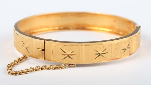 TooveysA gold circular hinged bangle with facet cut decoration, detailed ‘