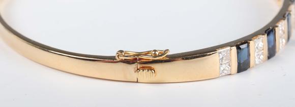 TooveysA gold, sapphire and diamond bangle, mounted with a row of nine cut