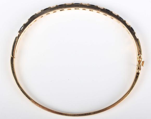 TooveysA gold, sapphire and diamond bangle, mounted with a row of nine cut