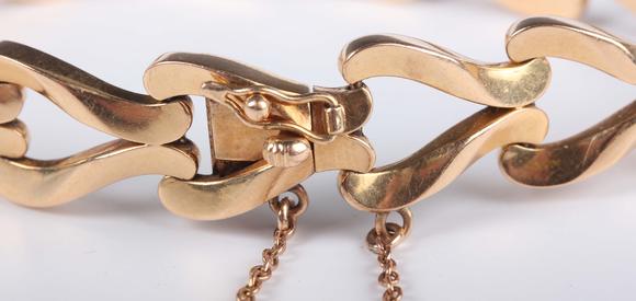 TooveysA gold bracelet in a twin scroll openwork link design, on a snap cla