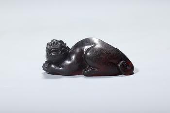 A Dark Red Amber Recumbent Mythical Beast, China, 14th–17th centuries