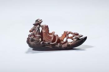 A Red Amber Openwork Boat Carving of an Immortal and Pine Trees, China, 14th–17th centuries