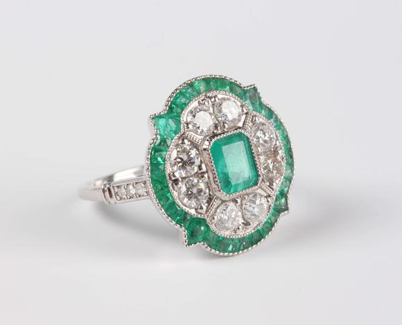 Tooveys|中西方古董藝術(shù)A platinum, emerald and diamond ring in an Art Deco inspired cluster design, mounted with the cut cornered rectangular step cut emerald within a quatr