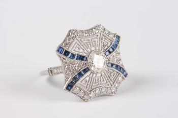 A platinum, sapphire and diamond ring, collet set with the principal circular cut diamond at the centre, otherwise in a pierced millegrain design, det