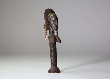 Bambara / Marka, Afrique de l’Ouest.
Poupée sculptée, ornée de tissus rouges, de perles, de cauris et de 
plaques de métal gaufrées à décor de scar