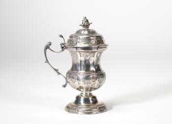 Moutardier en argent massif de forme balustre reposant sur un piédouche mouluré. Le corps est finement gravé de motifs rocaille et d’ornements stylis
